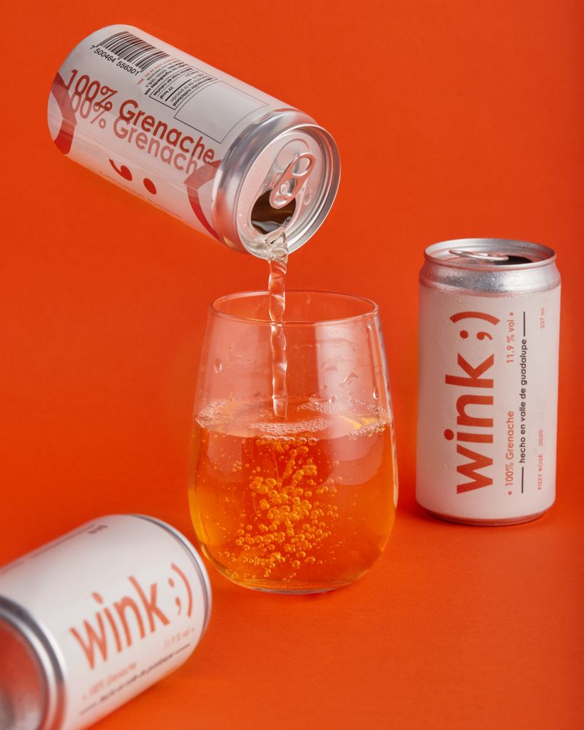 A vibrant image of a canned drink being poured into a glass on an orange studio backdrop.